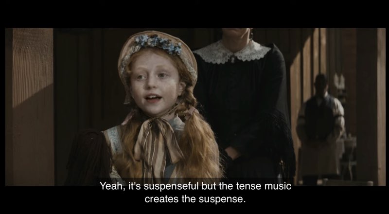 A young girl dressed in a bonnet and dress from the Old West is speaking. Closed captions at the bottom of the screen read, "Yeah, it's suspenseful but the tense music creates the suspense."
