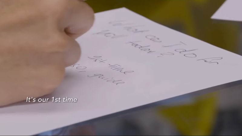 A close-up of the note is shown as Sheena writes, with subtitles reading, "It's our 1st time."