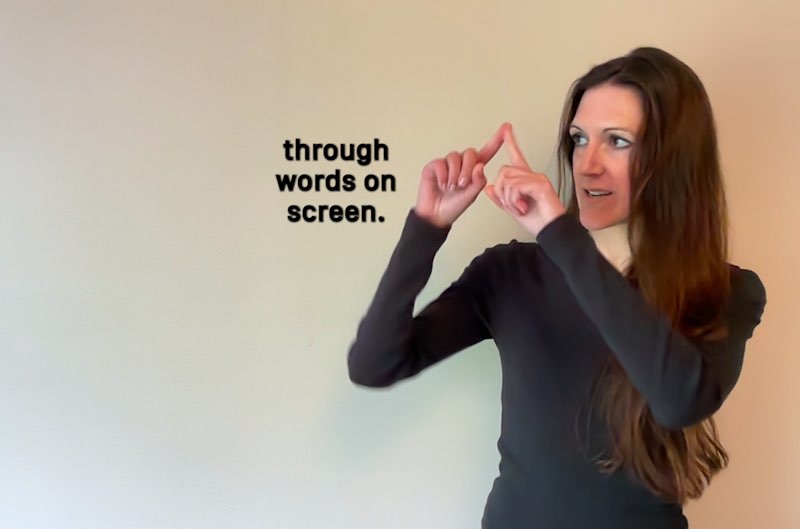 Janine Butler looks at the space next to her as she signs, "screen." Subtitles appear next to her hands that read, “through words on screen.”