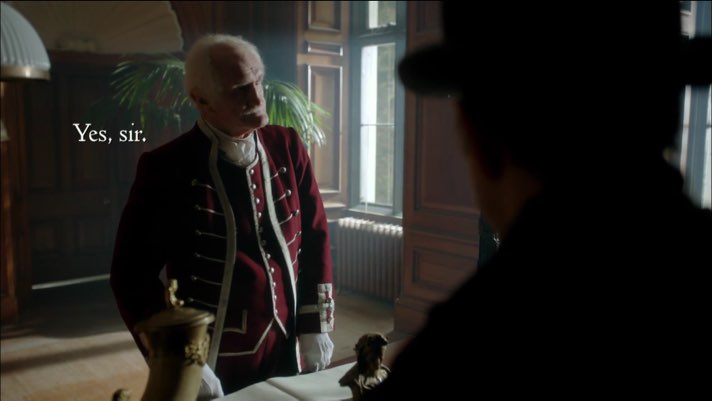 An elderly man dressed in a Victorian-era formal uniform standards with open subtitles appearing on the left side of the screen in the space near his shoulders. The subtitles read, "Yes, sir."