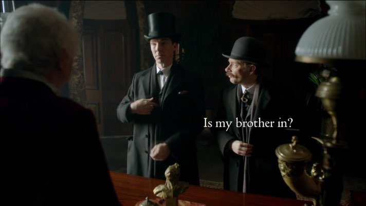 Sherlock and Watson are outfitted in Victorian top hats and overcoats. They face an elderly gentleman as Sherlock signs. Open white subtitles appear on the right side of the screen at the same level as his signs: “Is my brother in?”