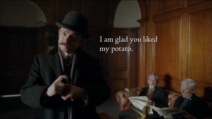 Watson is dressed in Victorian-era clothes as he attempts to sign. Open subtitles appear near his face on the right side of the screen, reading, “I am glad you liked my potato.”
