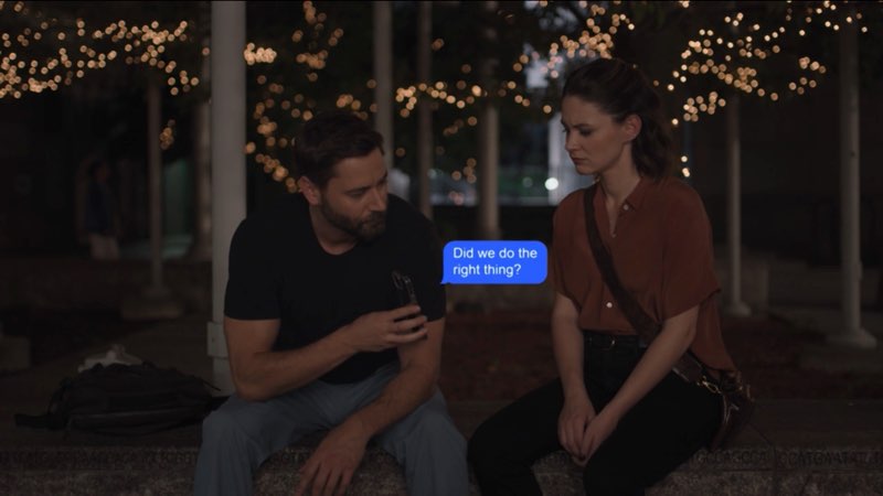 Max and Elizabeth, both looking sad and dressed in regular clothes, are seated outside the hospital at night. Max is holding his phone out to Elizabeth. A blue bubble appears between them and reads, "Did we do the right thing?"