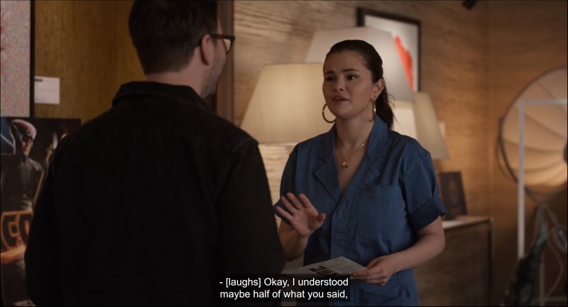Mabel stands in front of Theo as she speaks. Closed captions appear at the bottom reading, “[laughs] Okay, I understood maybe half of what you said.”