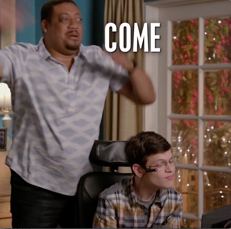 Cedric is standing next to Micah, waving away the word “come”