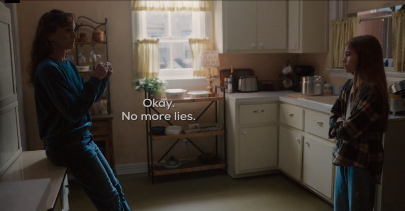 Birdie and Ollie are in their kitchen looking at each other. Birdie signs as subtitles appear near the front of her body that read, "Okay. No. More lies."