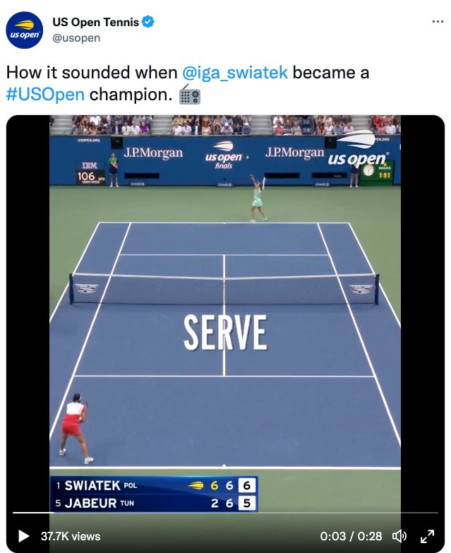A screenshot shows a tweet by US Open Tennis that reads, "How it sounded when @iga_swiatek became a #US Open champion." The tweet ends with an emoji of a radio. The tweet includes a video of Swiatek and Jabeur playing on a tennis court in the third set with Swiatek leading 6 games to 5. This image shows a moment in the video with large open captions over the middle of the court. The caption shows, "serve."